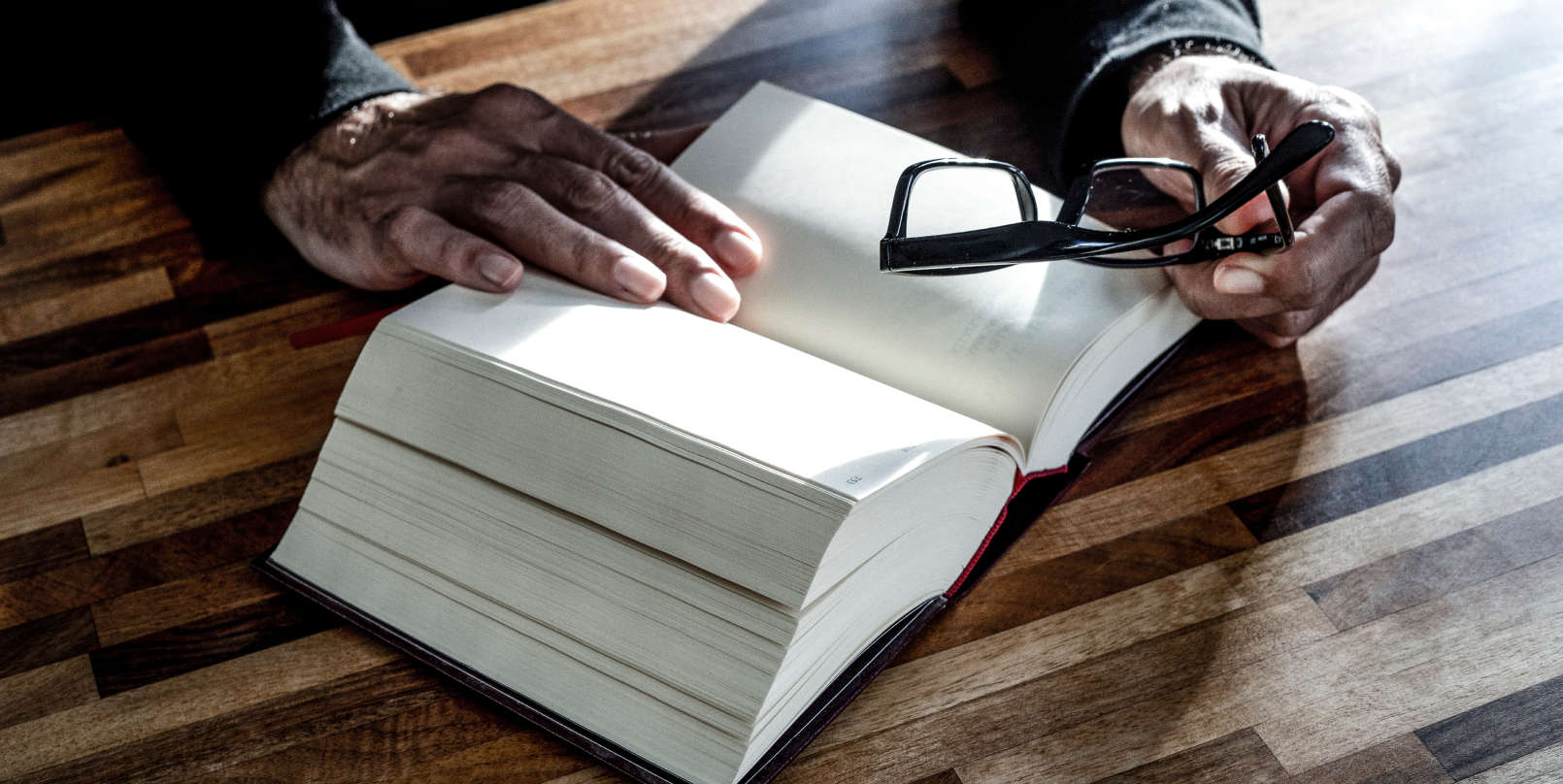 lawyer_holding_reading_glasses_looking_at_book-desktop